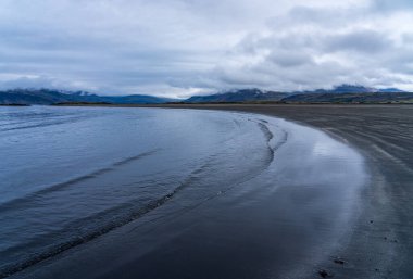 Doğu İzlanda 'nın Cupivogur kasabasındaki Bulandsnes' in kara kumlu plajı sahil şeridini yavaşça kaplıyor.