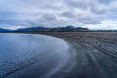 Doğu İzlanda 'nın Cupivogur kasabasındaki Bulandsnes' in kara kumlu plajı sahil şeridini yavaşça kaplıyor.