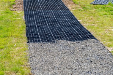 Plastik bir şebeke ile bir çakıl yolu oluşturuluyor dengeyi arttırmak ve açık havada uzun süre kullanılmasını sağlamak için..