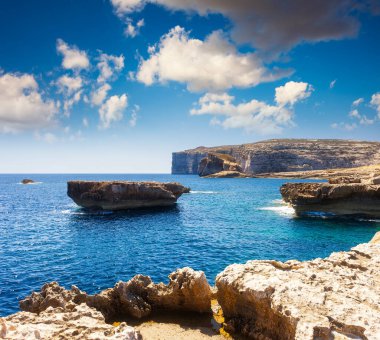 Kayalık sahilin muhteşem manzarası. Resimli ve muhteşem bir sahne. Pofuduk bulutlu güneşli bir günde gökyüzü açık. Yer: Azure Window, Gozo Adası, Dwejra. Malta. Avrupa. Güzellik dünyası.