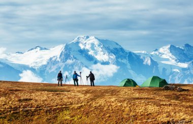 Bir grup fotoğrafçı kar sırtı manzarasını izliyor. Dramatik ve resimli bir sahne. Yeri Mkheer buzulu, Mestia, Svaneti, Gürcistan, Avrupa. Yüksek Kafkasya sırtı. Güzellik dünyası.