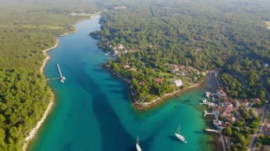 Yelkenli ve yatlı egzotik takımadalar. Güneşli bir günde İHA gökyüzü körfezinde uçuyor. Kvarner Körfezi, Punta Kriza, Cres Adası, Hırvatistan, Avrupa. Popüler turizm merkezi. Hava atışı, 4K.