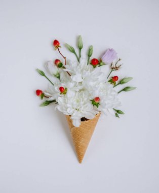 Beyaz arka planda dondurma külahında güzel bir buket çiçek. Çiçek aranjmanı, düz yatış stili. Üst Manzara. Yay duvar kâğıdı için yaratıcı ve hayat dolu bir fikir. Resimli ve muhteşem bir sahne. Güzellik dünyası.