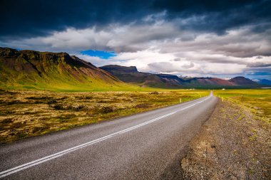 Sahil boyunca uzanan boş bir yol. Tipik İzlanda manzarası. Dramatik bir gün ve resimli bir sahne. İzlanda, Avrupa 'da bir yer. Aktif açık hava tatili. Dünyanın güzelliğini keşfedin.