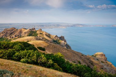 Kırım Yarımadası 'ndaki resim gibi bir dağ sırası, sönmüş antik bir volkan. Kara Dag (Black Mount), Koktebel kıyı kasabası. Dünyada eşi benzeri olmayan bir yer. Dünyanın güzelliğini ve vahşi yaşamını keşfedin..
