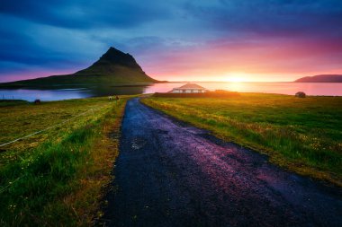 Akşam Kirkjufell volkanı Snaefellsnes yarımadasının kıyısında. Kirkjulsfoss 'un yeri. Tipik İzlanda manzarası. Dünyada eşi benzeri olmayan bir yer. Duvar kağıdının harika bir görüntüsü. Dünyanın güzelliğini keşfedin.