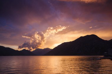 Güneş ışınları ve karanlık uğursuz gökyüzü tarafından aydınlatılan kırmızı canlı bulutlar. Harika bir doğal altyapı. Doğanın fenomeni. Resim gibi ve muhteşem bir sabah sahnesi. Güzellik dünyasını keşfedin