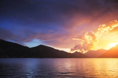 Güneş ışınları ve karanlık uğursuz gökyüzü tarafından aydınlatılan kırmızı canlı bulutlar. Harika bir doğal altyapı. Doğanın fenomeni. Resim gibi ve muhteşem bir sabah sahnesi. Güzellik dünyasını keşfedin