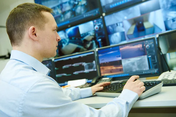 Überwachungssicherheit Wachmann Beobachtet Videoüberwachungssystem Und Benutzt Funksender lizenzfreie Stockfotos