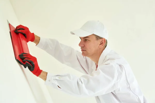 粉刷和墙面粉刷准备 专业的承包商工人工匠用石膏或填充物填塞 图库图片