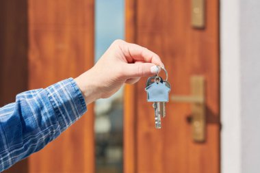 Yeni bir ev kapısının önünde ev anahtarlığının üzerinde el ele tutuşmak. İnşaat projesi, yeni bir eve taşınma, ipotek, kira veya emlak satın alma.