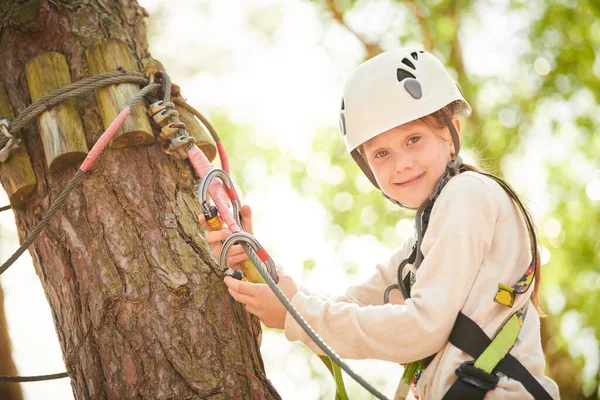 ロープパークの木の間に少女が登ってくる エンターテイメント トレーニングの高いワイヤーパーク — ストック写真