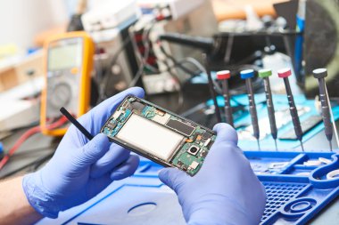 Cep telefonu tamiri için yakın çekim. Mikrodevreler ve piller değişmeden önce açık akıllı telefonu olan tamircinin elleri
