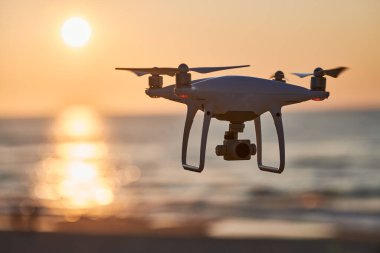 Gün batımında İHA. Deniz kıyısında uçan bir dron.