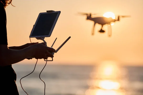 日落时操作无人机的人无人机在海面上飞行专注于无人驾驶飞机 图库图片