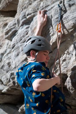 Male climber adjusting rope through quick draw clipart