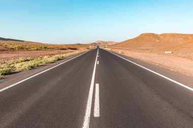 İspanya 'nın Fuerteventura adasındaki boş vadi boyunca uzanan yol yaz ve sıcak renk paleti ile seyahat arkaplanı görüntüsü