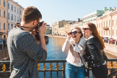 St. Petersburg 'da eğlenen ve fotoğraf çeken bir grup arkadaş, üç mutlu genç, bir erkek ve iki kadın, birlikte eğleniyorlar, arkadaşlık ve yaşam tarzı kavramları.