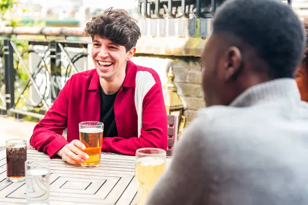 음료를 즐기는 행복한 다인종 런던의 술집에서 시간을 보내는 젊은이들과의 진정한 스톡 사진