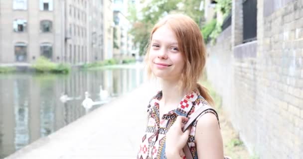 在伦敦的一个城市运河边微笑美丽的女人画像 一个有着天然姜黄头发的年轻女人的画像 近距离观察她的相机 幸福和生活方式的概念 — 图库视频影像