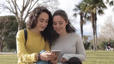 Madrid 'de iki güzel genç kızın gerçek portre fotoğrafı. Birlikte vakit geçiriyorlar ve akıllı telefondan sosyal medyaya bakıyorlar. Yaşam tarzı, arkadaşlık ve mutluluk kavramları.