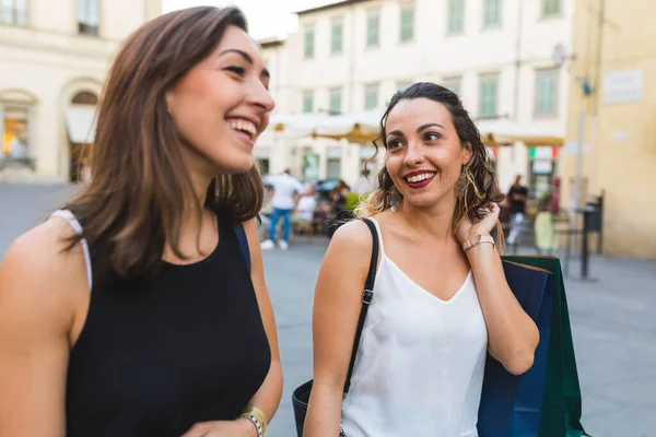 カラフルなショッピングバッグで街路を散策する2人の女性 イタリアで小売セラピーを楽しんでいる親友をショッピング ストック写真