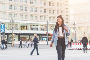Saçları örgülü gülümseyen genç zenci kadın, Berlin 'de güneşli bir günün tadını çıkarıyor.