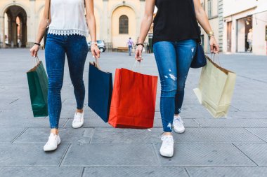 İki kadın ellerinde renkli alışveriş çantalarıyla şehir sokaklarında dolaşıyorlar en iyi arkadaşlarını İtalya 'da perakende terapinin keyfini çıkarıyorlar.