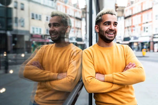 Happy man portrait in London - smiling young caucasian man leaning against glass shop window - lifestyle and happiness
