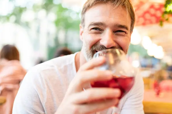 Fröhlicher Mann Mittleren Alters Mit Bart Schlürft Wein Einem Gemütlichen lizenzfreie Stockbilder