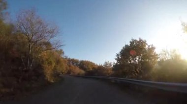 Güneşli bir günde kırsal bir yolda araba sürmek - araçta bir kamera ile çekilmiş video - bulutlu, seyahat ve ulaşım kavramlarıyla dolu mavi bir gökyüzü var