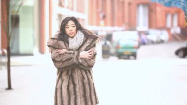 Şehirdeki Asyalı ve Kafkas kökenli genç bir kadının portresi. Londra 'da bir kış günü yürürken ve üşürken.