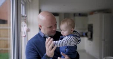 Baba adam yeni doğmuş bebeğiyle oturma odasında oynuyor. Çocuk, bebek, ebeveynlik, çocukluk, yaşam ve yaşam tarzının olduğu mutlu ebeveyn ve oğul sahnesi İngiltere 'de.