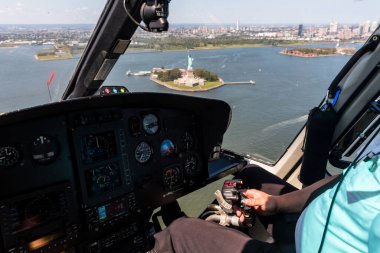 New York 'un üzerinde uçuyor. Bir pilot güneşli bir günde bir helikopteri Özgürlük Adası 'nın üzerinde ustalıkla manevra yaptırır.