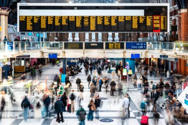 Londra Liverpool caddesi istasyonunda yürüyen yolcular tren saatlerini ve varış noktalarını gösteren hareket bulanıklığı efektiyle hareket halindeler.