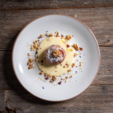 Ceviz ve vanilyalı krema sosuyla doldurulmuş fırınlanmış elmalar kırsal ahşap arka planda