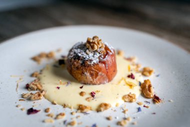 Ceviz ve vanilyalı krema sosuyla doldurulmuş fırınlanmış elmalar kırsal ahşap arka planda