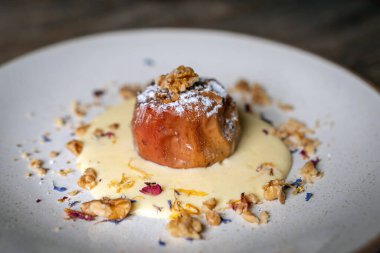 Ceviz ve vanilyalı krema sosuyla doldurulmuş fırınlanmış elmalar kırsal ahşap arka planda