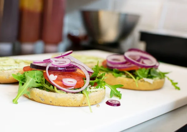 夹生菜 洋葱和西红柿的汉堡包两半 在餐馆厨房里做汉堡包 — 图库照片#