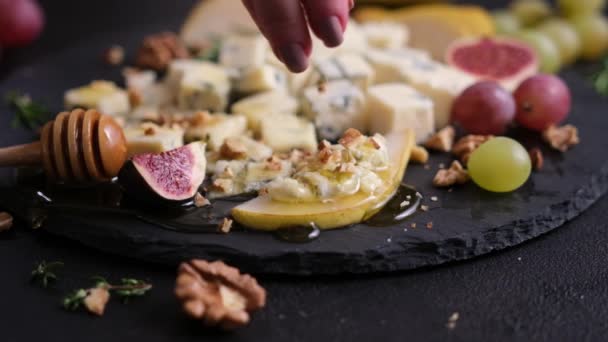 女性は砕いたくるみをスライスされた伝統的なイタリアのゴルゴンゾーラチーズに石の上に注ぐ — ストック動画