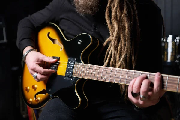 Guitarist man plays an electric guitar Close-up at studio.