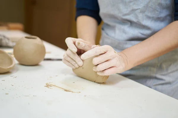 陶瓷艺术家将粘土钉在艺术工作室的桌子上的小手 — 图库照片