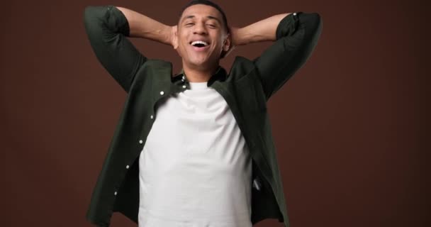 若いアフリカ系アメリカ人の男は茶色の背景に立って幸せな男を満足させた Dci 二重スローモーション — ストック動画