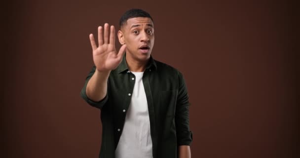 严肃的非洲裔美国人展示了张开的手掌 要求停下来或冷静下来 明确否认站在棕色工作室背景之上 Dci 2X慢动作 — 图库视频影像