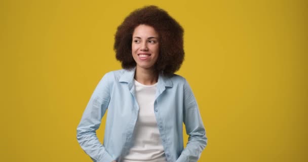 黄色のオレンジの背景の上に立ってカメラを見て巻き毛を持つ魅力的なアフリカ系アメリカ人女性を笑顔 Dci 二重スローモーション — ストック動画