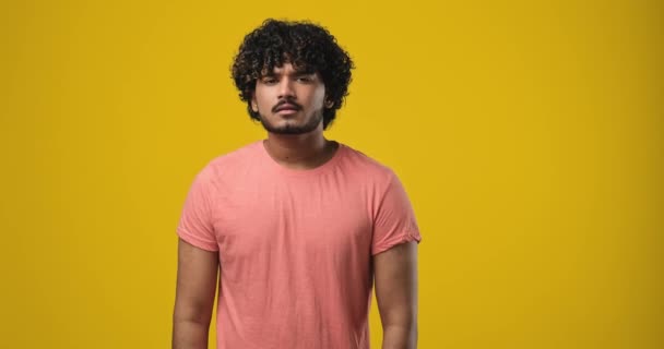 若いインド人男性は熱心に誰かに耳を傾け 黄色のオレンジのスタジオの背景の上に立つ親指を示すことに同意します Dci 二重スローモーション — ストック動画