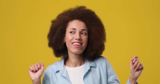 年轻的非洲裔美国女人 有着一头非洲裔的头发 在工作室里带着橙色背景开心地微笑和跳舞 Dci 2X慢动作 — 图库视频影像