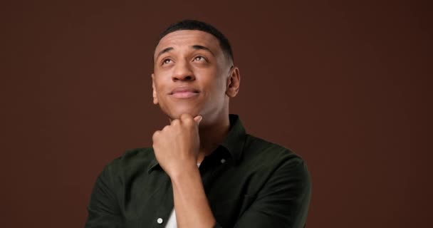 若いアフリカ系アメリカ人の男性が笑顔で茶色のスタジオの背景を見ているのクローズアップ肖像画 Dci 二重スローモーション — ストック動画