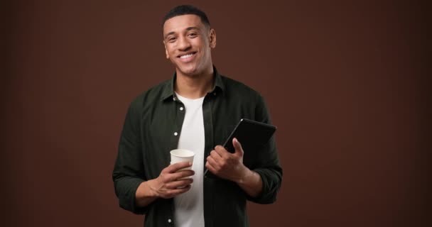 Młody Afroamerykanin Pijący Świeżo Zaparzoną Kawę Stojący Nad Brązowym Studiem — Wideo stockowe