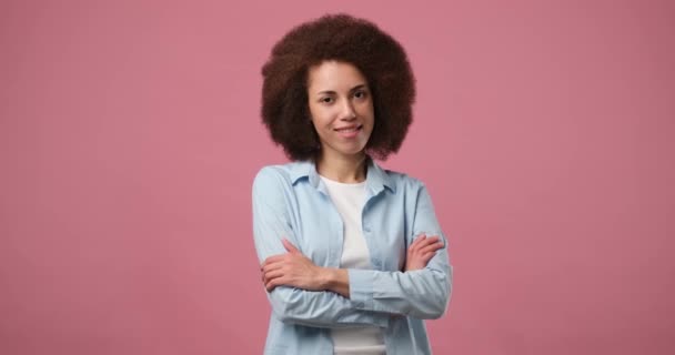 若いかなり笑顔のアフリカ系アメリカ人女性がピンクのスタジオの背景に自信を持って交差した Dci 二重スローモーション — ストック動画
